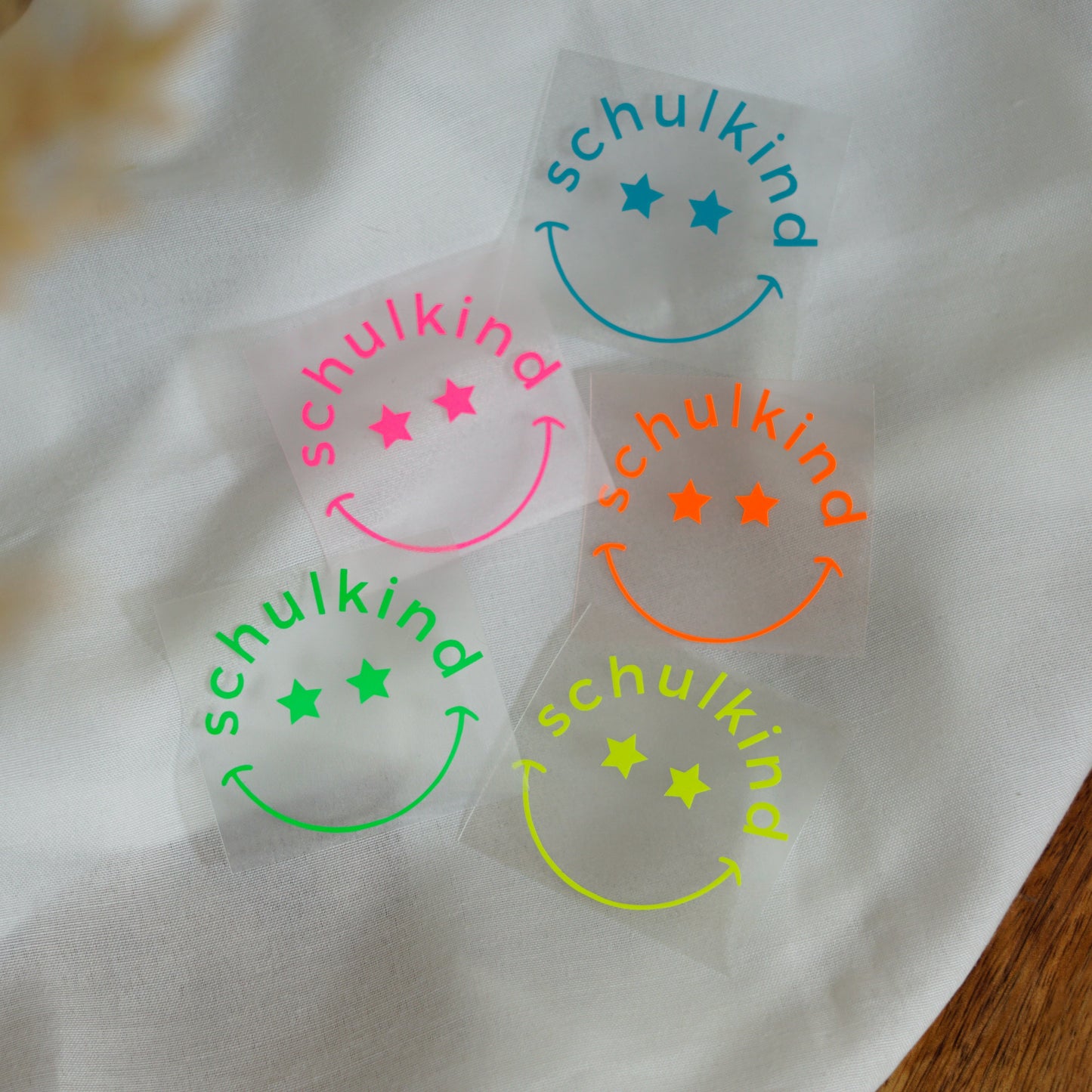 Neon Bügelbild – Schulkind mit lachendem Gesicht und Sternenaugen – leuchtendes Aufbügelmotiv für die Einschulung in Neon Pink, Gelb, Orange, Grün & Blau