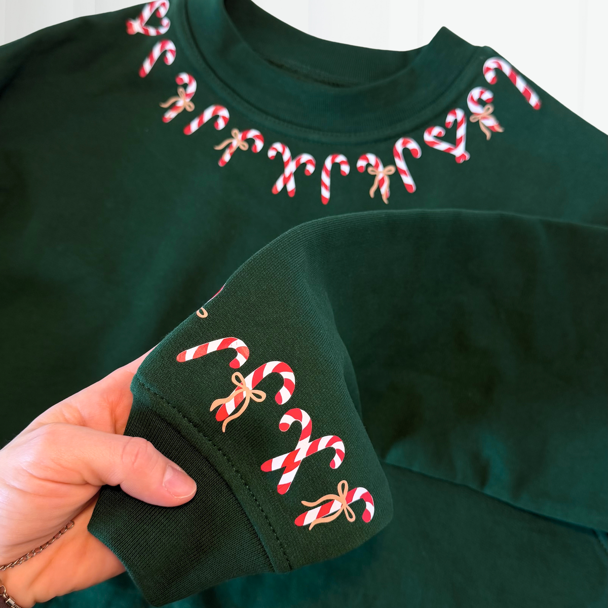 Candy Canes Plotterdatei mit rot-weißen Zuckerstangen und grünen Schleifen, gebogen entlang des Halsbündchens eines Christmas Sweatshirts.