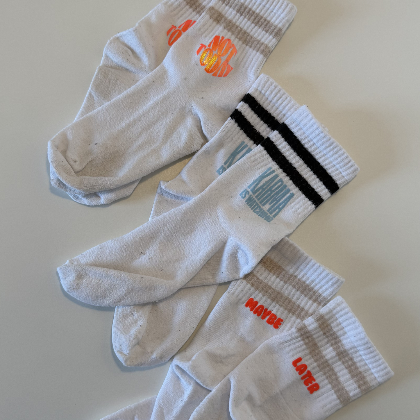 Set aus 23 kleinen Socken Sprüchen als Plotterdatei, minimalistische schwarze Schriftzüge für DIY Statement Socken, geeignet zum klein Plotten (3–4 cm), inkl. SVG DXF PNG Dateien für Cricut und Silhouette, dargestellt auf weißer Socke