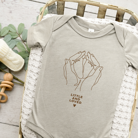 Digitale Plotterdatei „Little and Loved“ – Line Art Design mit den Händen der Mutter, die die Füße ihres Babys halten. Perfekt für Geburtsgeschenke und personalisierte Babyartikel.